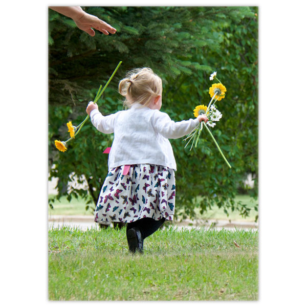 little girl running with daisies in her hands