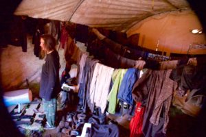 muddy wet clothes drying on multiple clothes lines in the "dry" tent at a tree planters campe